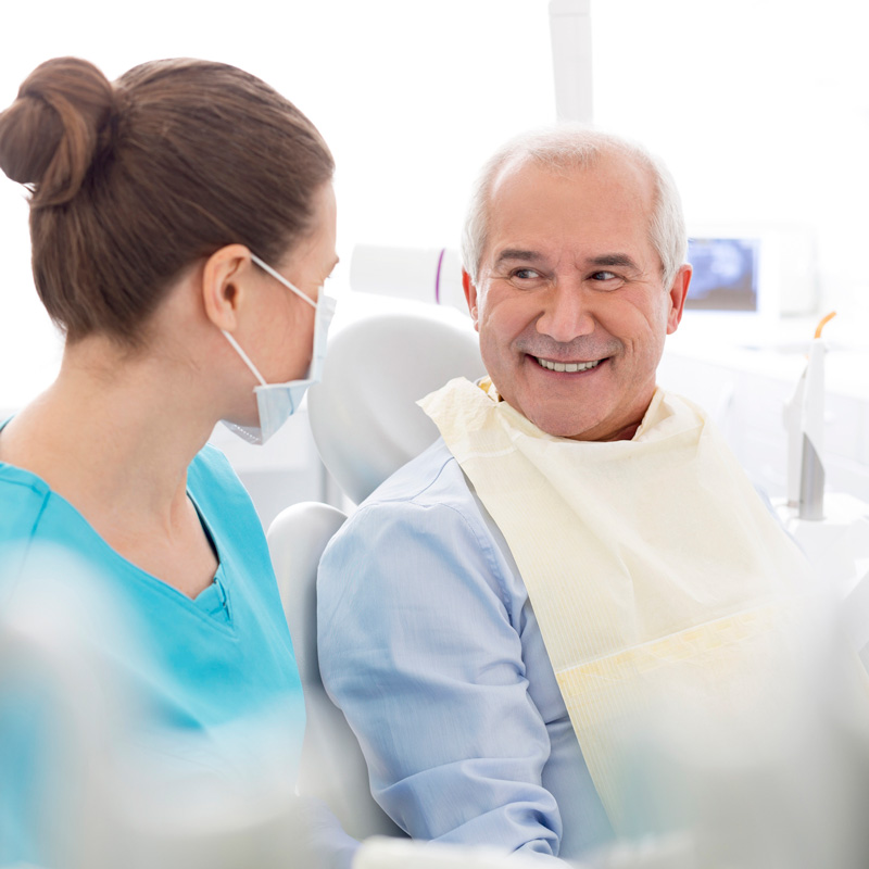 man in dental chair smiling at dentist