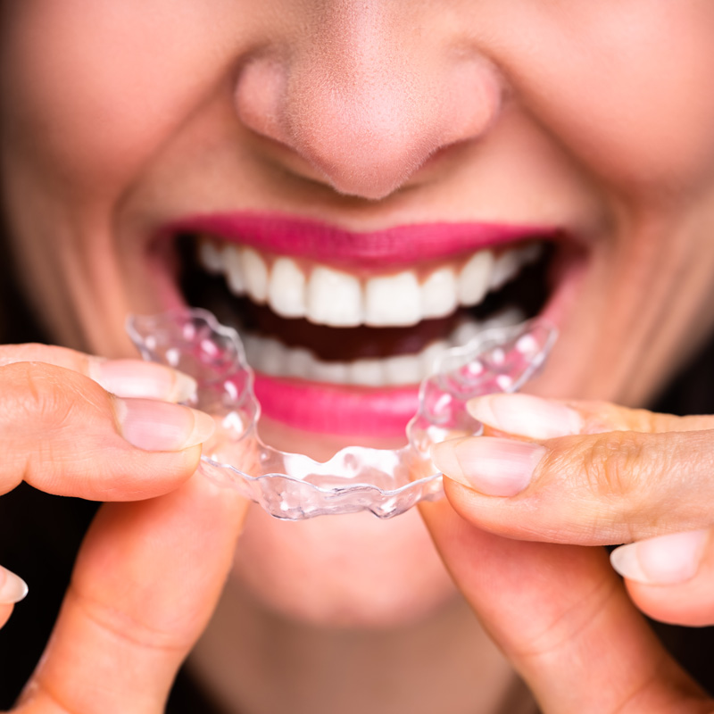 A woman in Millersville, MD, smiling while holding clear braces