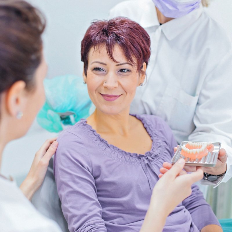 Dental professionals showing a set of dentures to a patient during a consultation in Millersville, MD